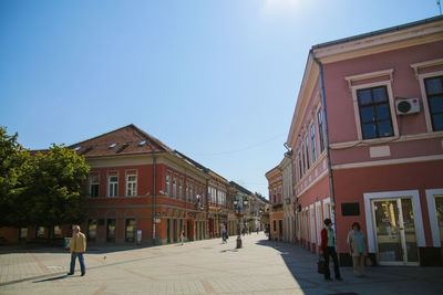 People walking on street amidst buildings against sky