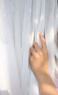 Close-up of person hand on white curtain
