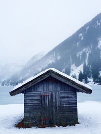 Snow covered hut on shore during foggy weather