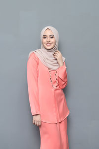 Portrait of smiling young woman standing against white background