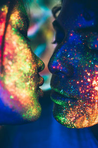 Close-up of couple with multi colored face paint kissing