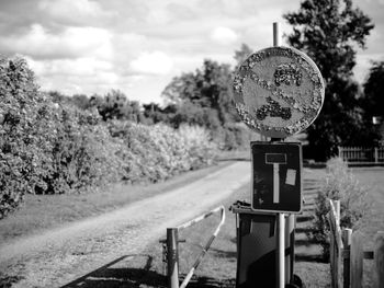 Close-up of road sign against trees on field