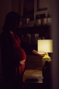 Rear view of woman reading book at home