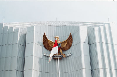 Woman sitting on roof against sky