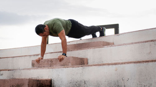 Man doing push up on the step outdoor during rainy day