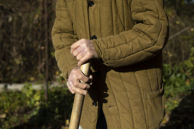 Old man's hands. old man holding stick. poor clothes. elderly person works on land. 