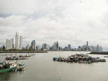 High angle view of boats moored on river against urban skyline