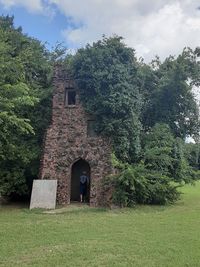 Built structure by trees on field against sky