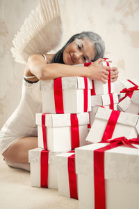 Portrait of female model in angel costume holding christmas presents