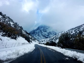 Road amidst snow covered mountains against sky