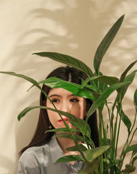 Portrait of young woman with leaves in plant