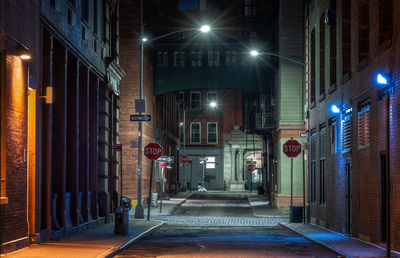 Rear view of man walking in illuminated city at night