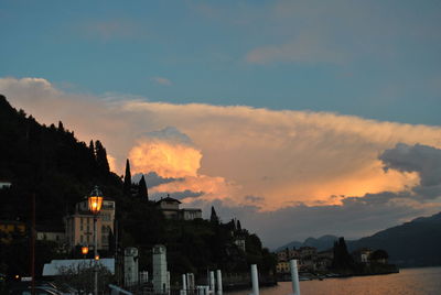 Buildings by sea against sky at sunset