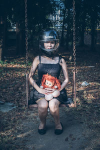 Portrait of young woman sitting on tree stump