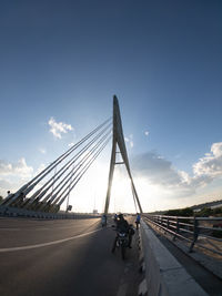 People riding on bridge against sky