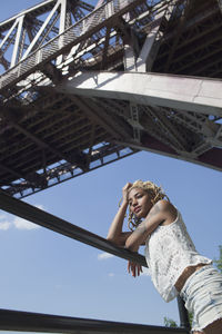 A young woman posing beneath a bridge