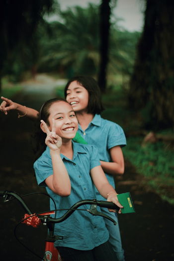 Happy sisters with bicycle at park