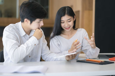 Young couple looking at camera while sitting on table