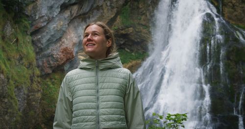 Portrait of woman standing against waterfall