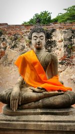 Buddha statue by temple against sky