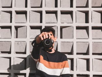 Full length of man photographing against wall