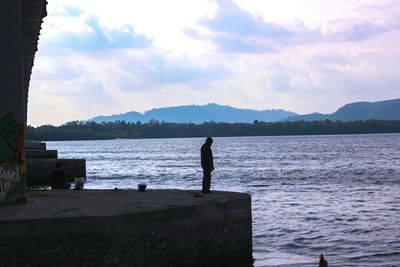 Rear view of silhouette man standing on lake