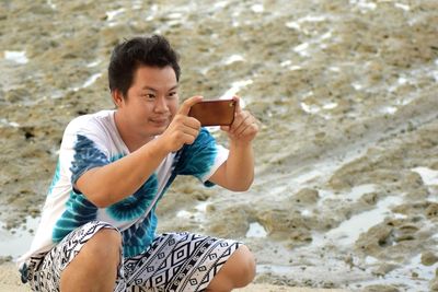 Young man using mobile phone at beach