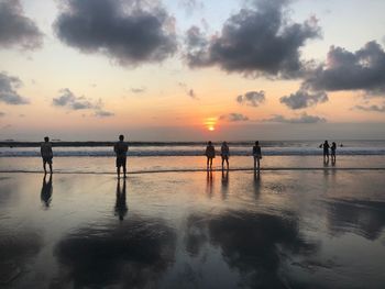 Silhouette people on beach against sky during sunset