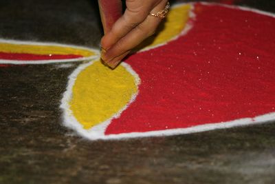 Cropped hand of woman making rangoli on floor