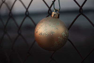 Close-up of christmas decoration hanging on chainlink fence