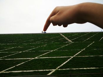 Close-up of person hand on land against sky