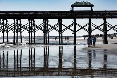 People walking on pier against sky during rainy season