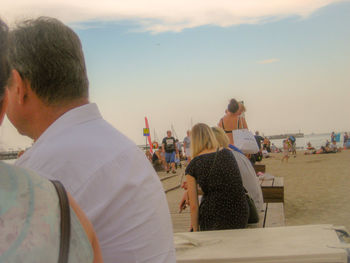 Rear view of people at beach against sky