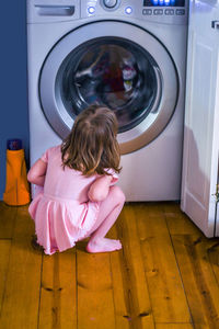 Little girl in pink anxiously watches as a machine cleans her favorite blanket