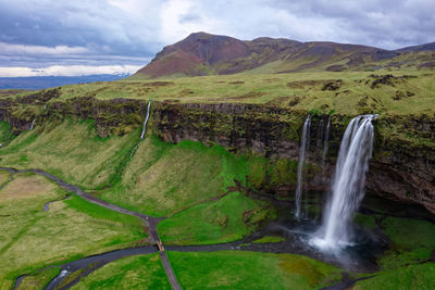 Scenic view of waterfall on mountain against sky