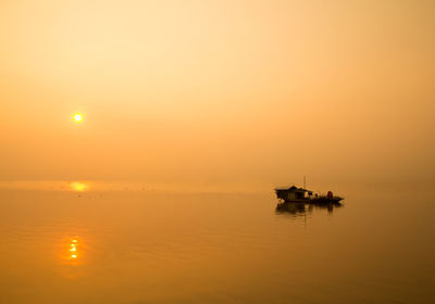 Silhouette boat sailing on sea against clear sky during sunset