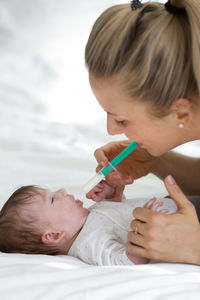 Close-up of mother feeding baby on bed at home