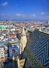 High angle view of city buildings against blue sky