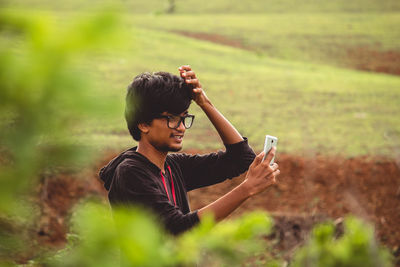 Young man taking selfie with mobile phone on field