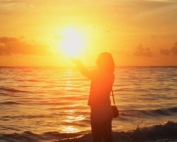 Silhouette person standing on beach during sunset