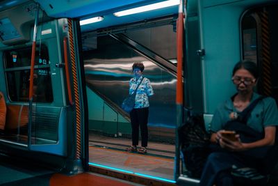 Full length of young woman sitting in train