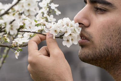 Close-up of young man against white flowering plants