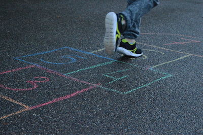 Low section of person playing hopscotch on footpath