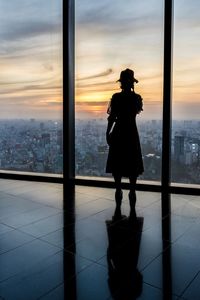 Silhouette man standing by window in city