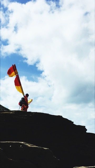 MAN STANDING ON MOUNTAIN AGAINST SKY