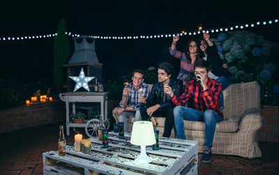 Young friends holding sparkler during party in backyard at night