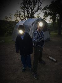 Man holding umbrella against illuminated lights