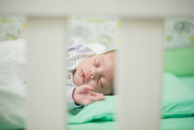 Close-up of cute baby boy sleeping on crib