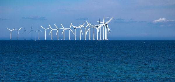 Wind turbines in sea against sky