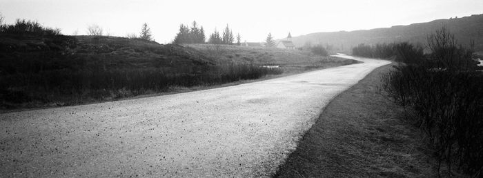 Road amidst trees against clear sky